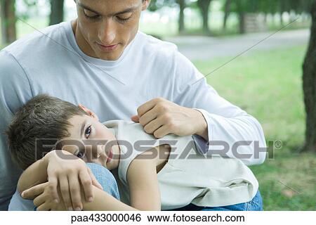 Stock Photograph - Boy lying down in father's lap. Fotosearch