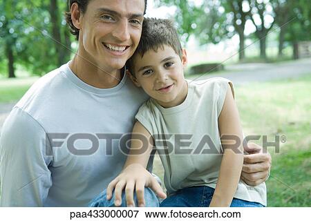 Boy sitting on father's lap View Large Photo Image Stock Photo - Boy sitting on father's lap. Fotosearch