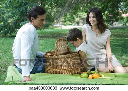 Stock Image - Family having picnic on lawn. Fotosearch