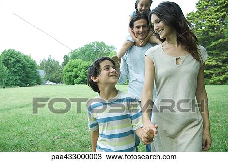 Stock Image - Family outdoors walking across a grassy lawn. Fotosearch