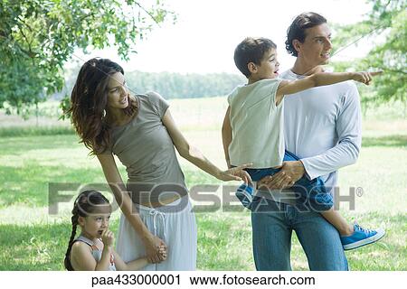 Stock Image - Family standing outdoors on lawn on a sunny day. Fotosearch