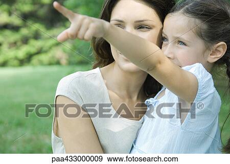 Stock Photo - Woman and daughter, girl pointing out of frame. Fotosearch
