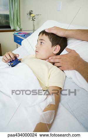 Boy lying in hospital bed having pulse taken View Large Photo Image Picture - Boy lying in hospital bed having pulse taken. Fotosearch