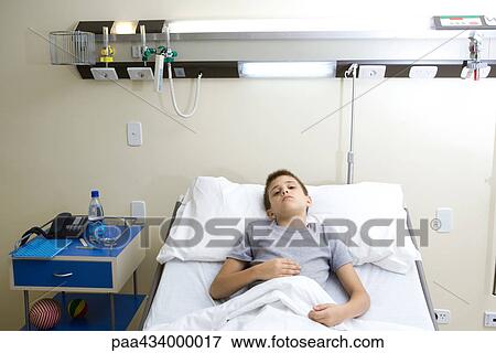 Boy lying in hospital bed, holding stomach View Large Photo Image Stock Photo - Boy lying in hospital bed, holding stomach. Fotosearch