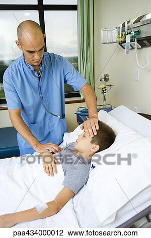 Boy lying in hospital bed, intern taking his temperature View Large Photo Image Stock Image - Boy lying in hospital bed, intern taking his temperature. Fotosearch