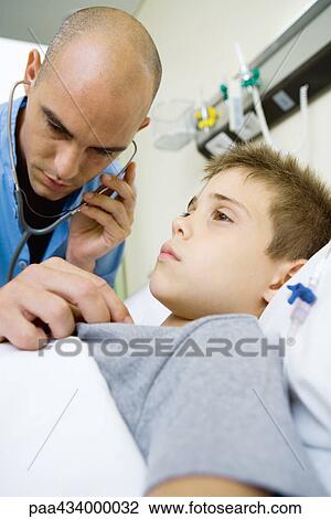 Boy lying in hospital bed, intern listening to boy's chest with stethoscope View Large Photo Image Stock Image - Boy lying in hospital bed, intern listening to boy's chest with stethoscope. Fotosearch
