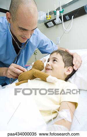 Boy lying in hospital bed, intern holding stethoscope to boy's stuffed animal View Large Photo Image Stock Photography - Boy lying in hospital bed, intern holding stethoscope to boy's stuffed animal. Fotosearch