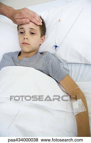Boy lying in hospital bed, man's hand on boy's forehead View Large Photo Image Stock Photo - Boy lying in hospital bed, man's hand on boy's forehead. Fotosearch