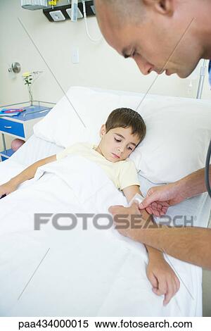 Boy lying in hospital bed while doctor puts bandage on boy's arm View Large Photo Image Stock Photography - Boy lying in hospital bed while doctor puts bandage on boy's arm. Fotosearch