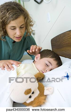 Boy sleeping in hospital bed, intern looking over boy's shoulder View Large Photo Image Stock Photograph - Boy sleeping in hospital bed, intern looking over boy's shoulder. Fotosearch