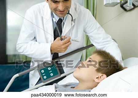 Doctor talking with boy lying in hospital bed View Large Photo Image Stock Photo - Doctor talking with boy lying in hospital bed. Fotosearch