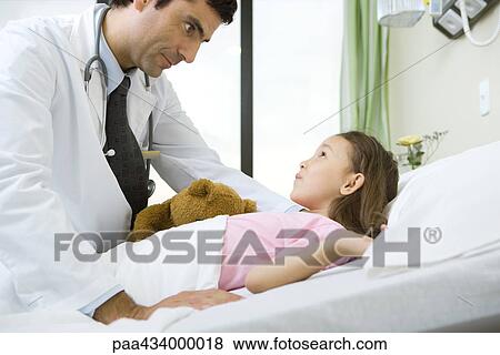 Doctor talking with girl lying in hospital bed View Large Photo Image Stock Photo - Doctor talking with girl lying in hospital bed. Fotosearch