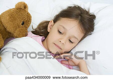 Girl lying in bed with teddy bear View Large Photo Image Stock Photo - Girl lying in bed with teddy bear. Fotosearch