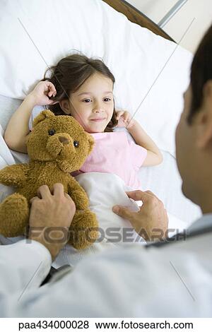 Girl lying in hospital bed, smiling up at doctor View Large Photo Image Stock Photo - Girl lying in hospital bed, smiling up at doctor. Fotosearch