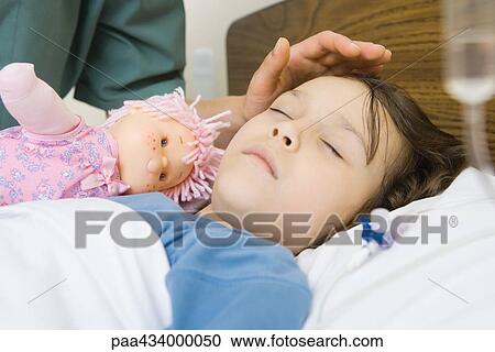 Girl sleeping in hospital bed, woman's hand posed over girl's forehead View Large Photo Image Stock Image - Girl sleeping in hospital bed, woman's hand posed over girl's forehead. Fotosearch