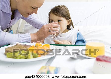 Woman feeding girl sitting in hospital bed View Large Photo Image Stock Image - Woman feeding girl sitting in hospital bed. Fotosearch