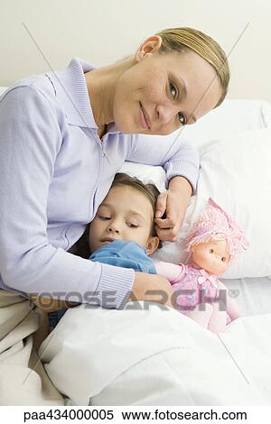 Woman sitting next to girl in bed, smiling at camera View Large Photo Image Stock Photography - Woman sitting next to girl in bed, smiling at camera. Fotosearch