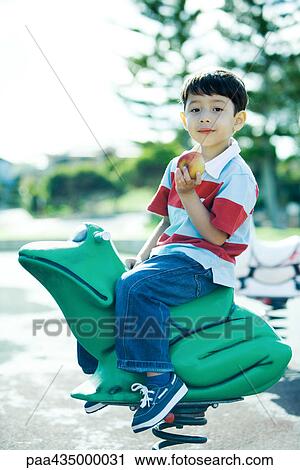 Boy on playground equipment, smiling at camera, holding apple View Large Photo Image Stock Image - Boy on playground equipment, smiling at camera, holding apple. Fotosearch