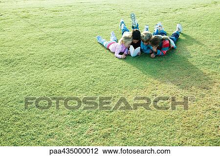 Children lying on grass, reading book together View Large Photo Image Stock Image - Children lying on grass, reading book together. Fotosearch