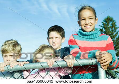Children standing behind wire fence, smiling at camera View Large Photo Image Stock Photography - Children standing behind wire fence, smiling at camera. Fotosearch