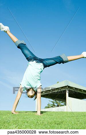 Girl doing cartwheel on grass View Large Photo Image Stock Photo - Girl doing cartwheel on grass. Fotosearch