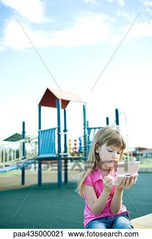 Girl sitting on playground playing with handheld video game View Large Photo Image Stock Image - Girl sitting on playground playing with handheld video game. Fotosearch