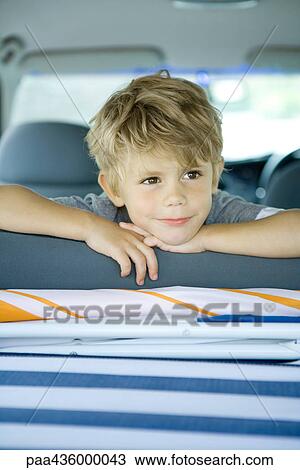 Stock Image - Boy in car, looking over back of seat. Fotosearch