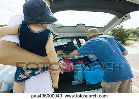 Family unloading beach material out of trunk of car View Large Photo Image Stock Photo - Family unloading beach material out of trunk of car. Fotosearch