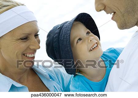 Little girl between mother and father, looking up at father, smiling View Large Photo Image Stock Photo - Little girl between mother and father, looking up at father, smiling. Fotosearch