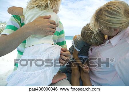 Stock Photograph - Man and woman holding son and daughter on beach. Fotosearch