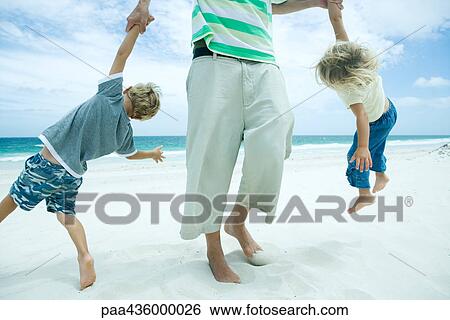 Man picking up son and daughter by arms on beach View Large Photo Image Stock Photograph - Man picking up son and daughter by arms on beach. Fotosearch