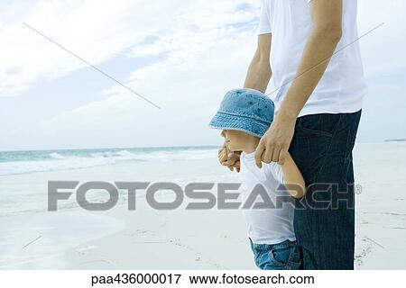 Stock Photo - Man standing on beach with son. Fotosearch