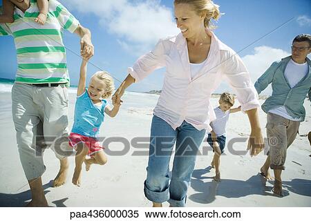 Stock Photography - Three generation family walking on beach. Fotosearch