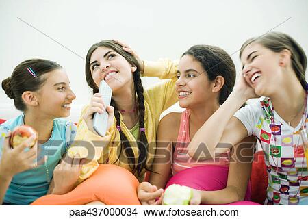 Four young female friends sitting together, smiling, snacking View Large Photo Image Picture - Four young female friends sitting together, smiling, snacking. Fotosearch