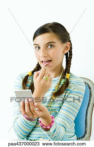 Preteen girl putting on lipstick, looking at camera View Large Photo Image Stock Image - Preteen girl putting on lipstick, looking at camera. Fotosearch
