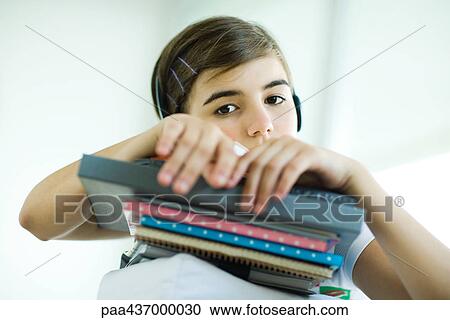 Stock Image - Teen girl holding stack of books and notebooks. Fotosearch