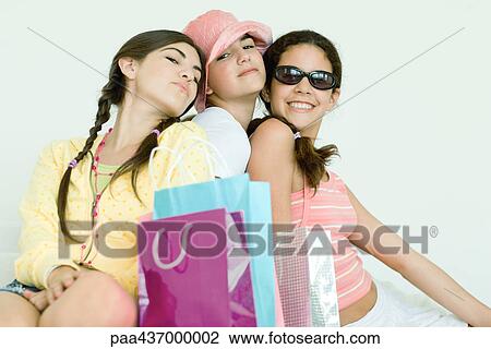 Stock Image - Three young female friends posing, shopping bags in foreground. Fotosearch