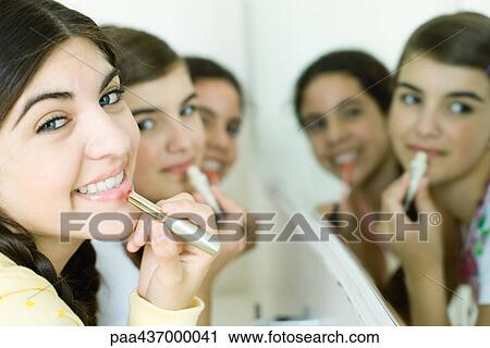 Three young female friends putting on make-up, smiling at camera View Large Photo Image Stock Image - Three young female friends putting on make-up, smiling at camera. Fotosearch
