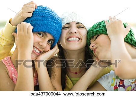 Three young female friends wearing knit hats, smiling View Large Photo Image Picture - Three young female friends wearing knit hats, smiling. Fotosearch