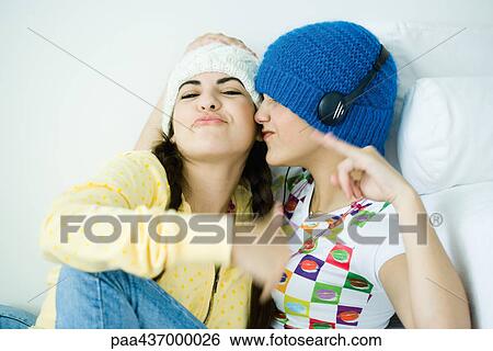 Stock Photograph - Two young female friends listening to music. Fotosearch