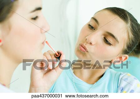 Stock Image - Two young female friends, one putting make-up on the other. Fotosearch