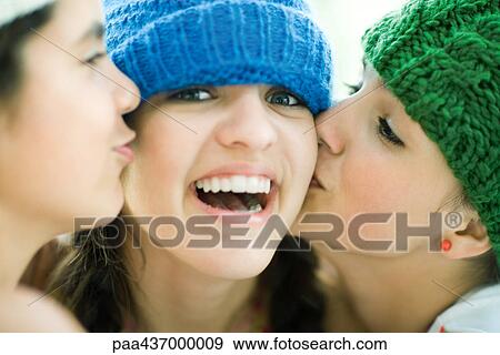 Young female being kissed on cheeks by two friends, smiling at camera View Large Photo Image Stock Photo - Young female being kissed on cheeks by two friends, smiling at camera. Fotosearch