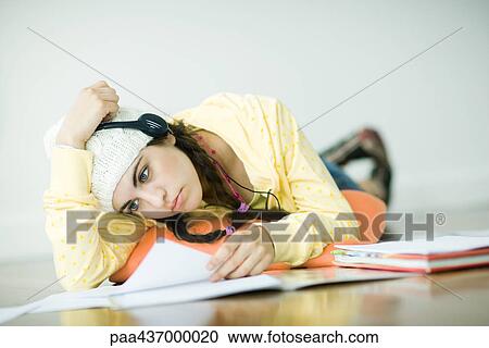 Young woman lying on floor, wearing headphones and studying View Large Photo Image Stock Image - Young woman lying on floor, wearing headphones and studying. Fotosearch