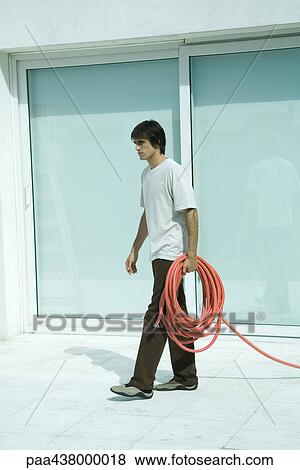 Stock Photo - Man carrying garden hose, full length. Fotosearch