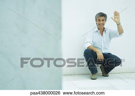 Man crouching, waving, full length View Large Photo Image Stock Photograph - Man crouching, waving, full length. Fotosearch