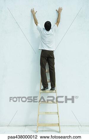 Man standing on ladder, reaching up along wall, full length View Large Photo Image Stock Image - Man standing on ladder, reaching up along wall, full length. Fotosearch