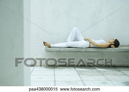 Stock Photography - Woman lying on bench, full length, side view. Fotosearch