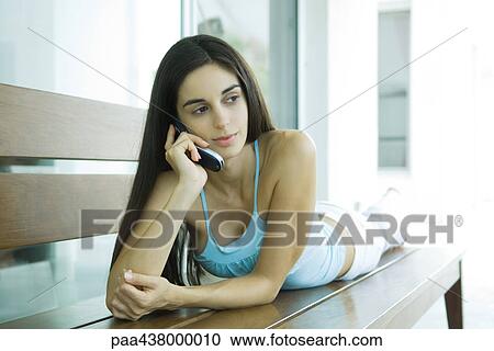 Woman lying on bench, using cell phone, full length View Large Photo Image Stock Image - Woman lying on bench, using cell phone, full length. Fotosearch