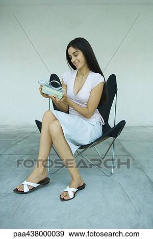 Woman sitting, holding gift, full length View Large Photo Image Stock Photo - Woman sitting, holding gift, full length. Fotosearch