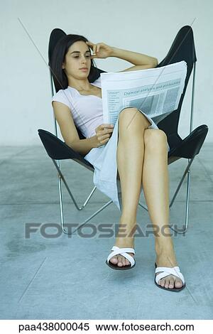 Woman sitting in chair, reading newspaper, full length View Large Photo Image Stock Photography - Woman sitting in chair, reading newspaper, full length. Fotosearch